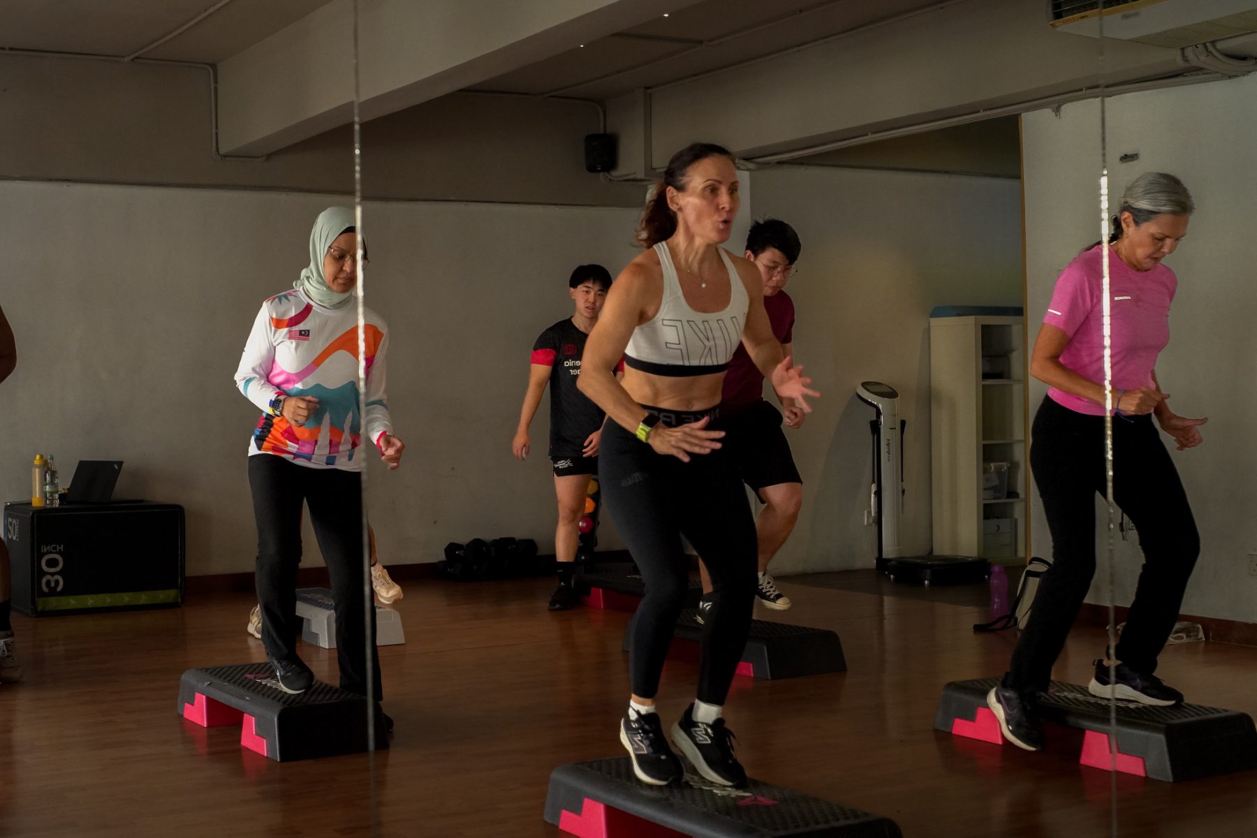 A small-group step class in the Body for Life studio, led by a coach at the front