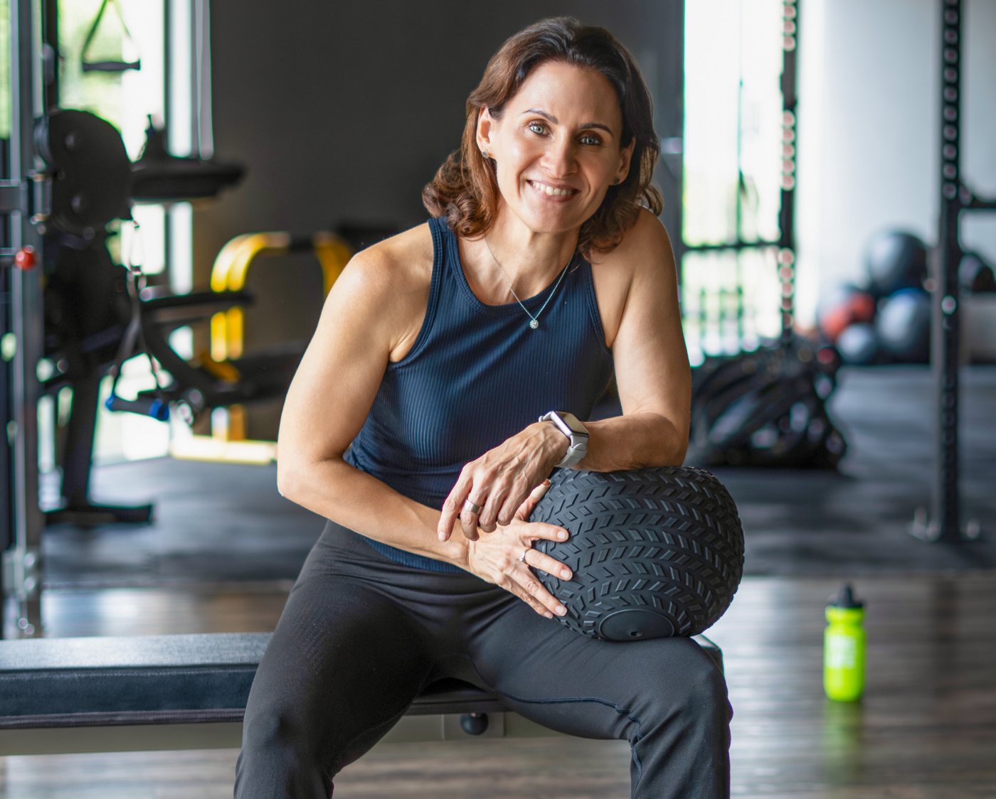 Simone Quinten, founder of Body for Life Fitness, seated on a bench in the studio holding a medicine ball